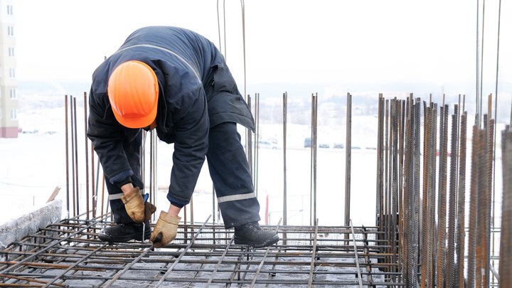 worker in workwear making reinforcement metal framework for concrete pouring