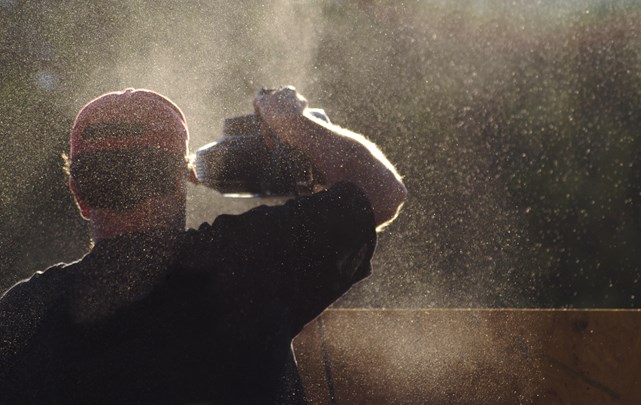 Backlit view of a construction worker using a circular saw with sawdust flying in the air