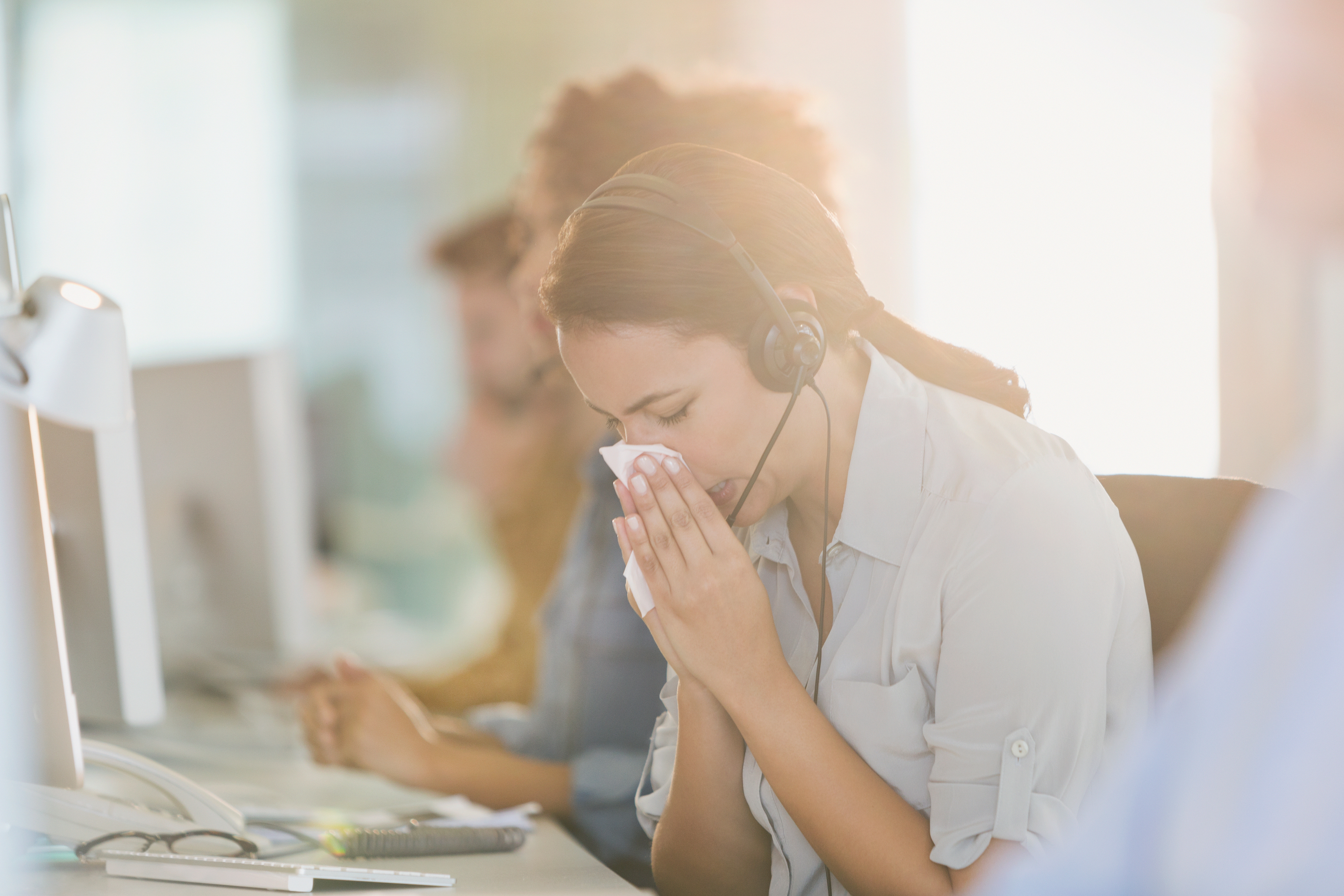 Eine Frau am Arbeitsplatz die am Sick-Building-Syndrom leidet 