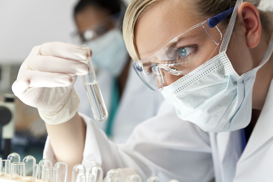 Female scientist, lab worker examining test tube.